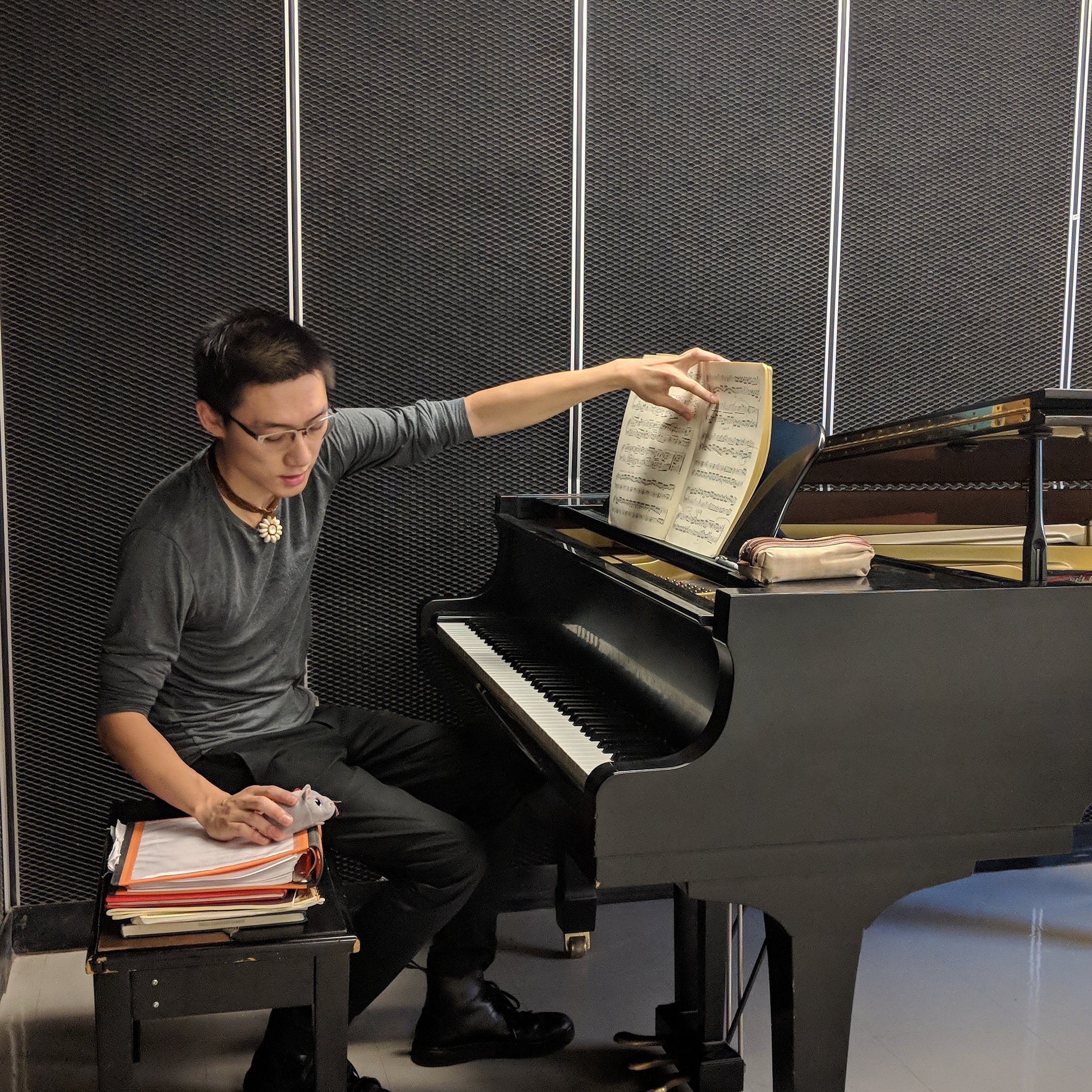 A picture of George Wu Teng humorously teaching a stuffed mouse piano